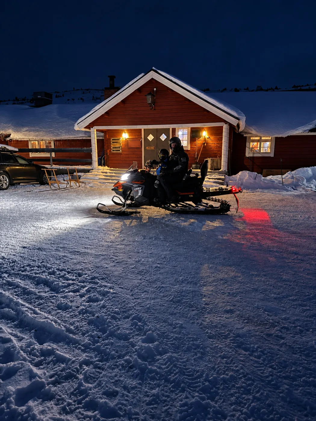 Vargens hus en vinterkväll, en skoter står framför entrén