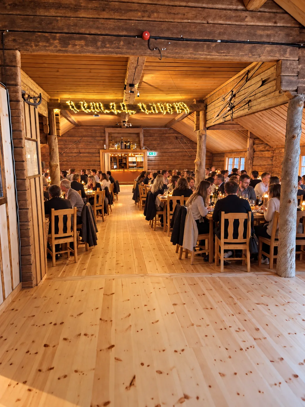 Full matsal på Vargen en kväll, timrade väggar och ljusslingor i taket