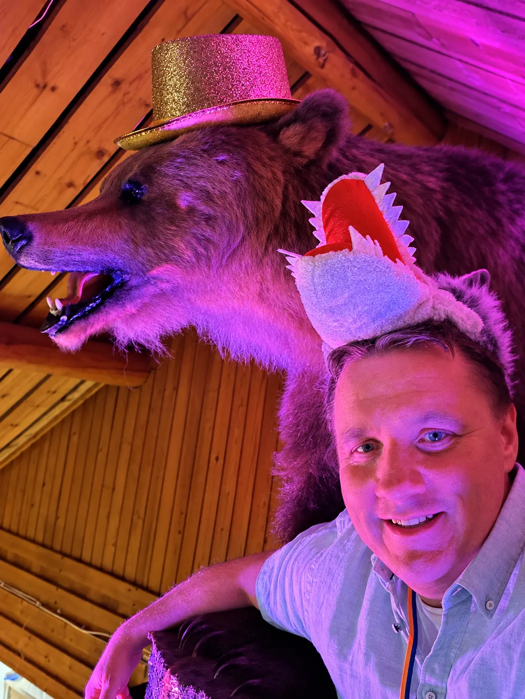 En gäst i varghatt tar en bild med den uppstoppade björnen i glitterhatt