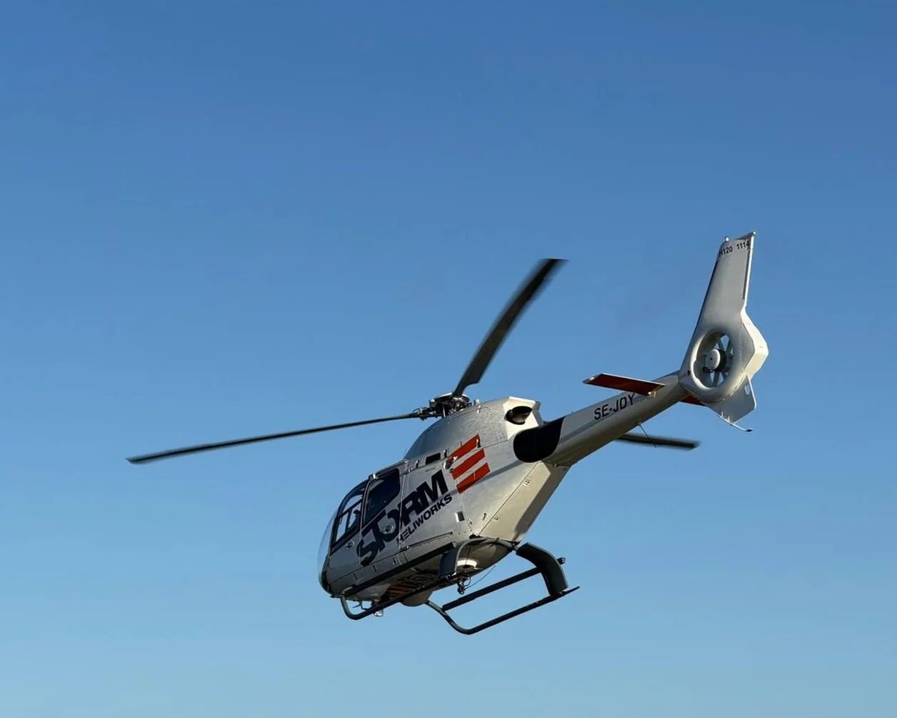 Storm Heliworks helikopter i luften mot blå himmel